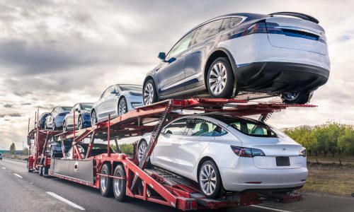 Dec 8, 2019 Bakersfield / CA / USA - Car transporter carries new Tesla vehicles along the interstate to South California, back view of the trailer